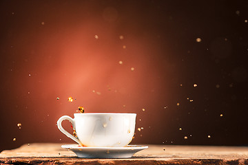 Image showing Brown splashes out drink from cup of tea on a brown background