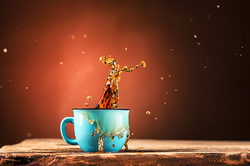 Image showing Brown splashes out drink from cup of tea on a brown background