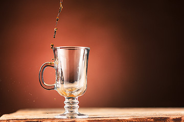 Image showing Brown splashes out drink from cup of tea on a brown background