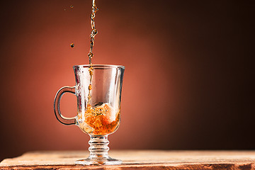 Image showing Brown splashes out drink from cup of tea on a brown background