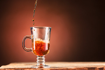 Image showing Brown splashes out drink from cup of tea on a brown background