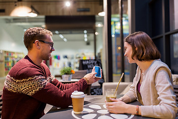 Image showing happy couple with smartphone and drinks at cafe