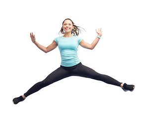 Image showing happy smiling sporty young woman jumping in air