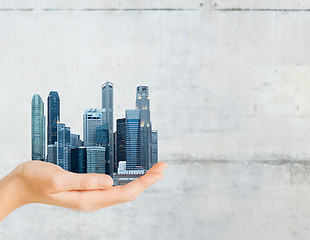 Image showing hand holding city over gray concrete background