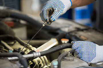 Image showing mechanic with dipstick checking motor oil level