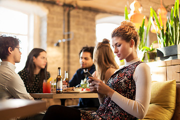 Image showing woman with smartphone and friends at restaurant