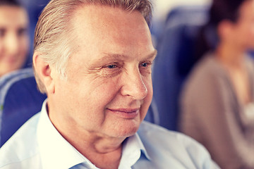 Image showing happy senior man sitting in travel bus or airplane