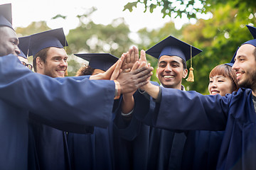 Image showing happy students in mortar boards making high five