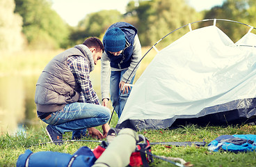 Image showing happy father and son setting up tent outdoors