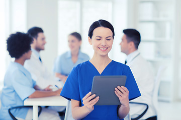 Image showing happy doctor with tablet pc over team at clinic