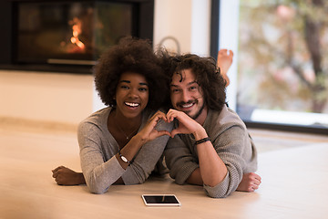 Image showing multiethnic couple used tablet computer on the floor