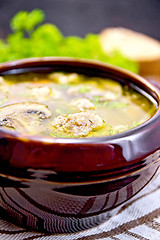 Image showing Soup with meatballs and mushrooms in clay bowl on dark board