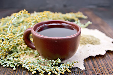 Image showing Tea with wormwood in clay cup on board