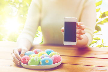 Image showing close up of hands with easter eggs and smartphone