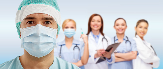 Image showing surgeon in mask with group of medics over blue