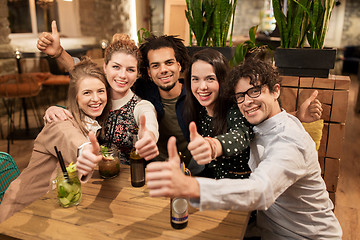 Image showing happy friends with drinks showing thumbs up at bar