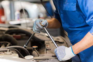 Image showing mechanic man with wrench repairing car at workshop