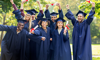 Image showing happy students in mortar boards with diplomas