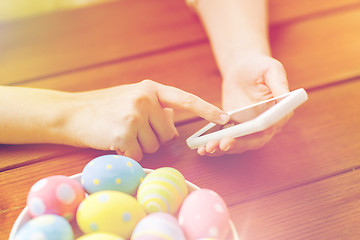 Image showing close up of hands with easter eggs and smartphone