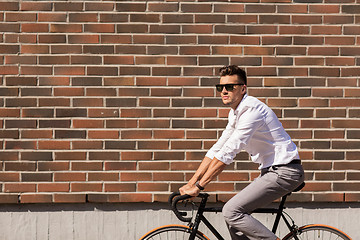 Image showing young man riding bicycle on city street