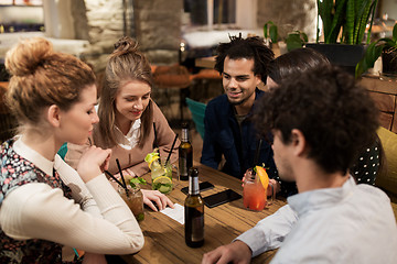 Image showing happy friends with drinks and bill at bar or cafe