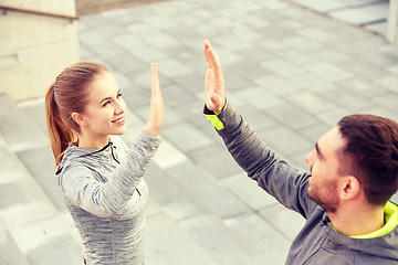 Image showing smiling couple making high five on city street