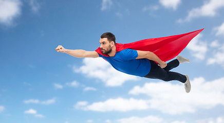 Image showing man in red superhero cape flying over blue sky