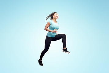 Image showing happy smiling sporty young woman jumping in air