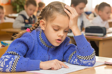 Image showing First-grader at a lesson reads the text line by line leading a finger, in the background other students