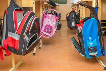 Image showing School bags hanging on hangers on both sides of the aisle between the desks in the classroom