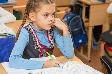 Image showing Girl schoolgirl sits at a school desk at a lesson at school