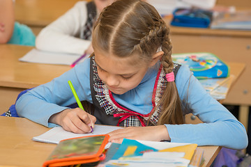 Image showing First-grader at a lesson of mathematics to solve the examples notebook