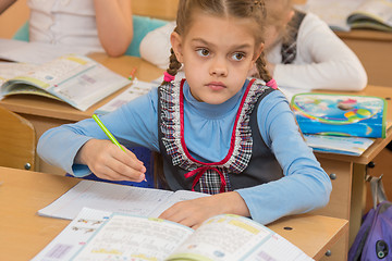 Image showing First-grader at a lesson of mathematics solves examples and look at the board