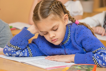 Image showing First grader at reading lesson reading text sitting at a school desk