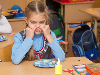 Image showing The girl at a lesson at school stuck his fingers in the nostrils of the nose