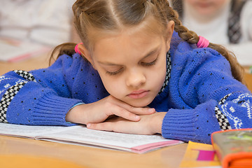 Image showing First grader to read the lesson reads the text in the book with his head in his hands