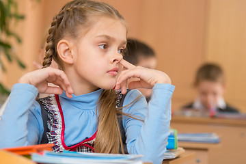 Image showing The girl at a lesson at school picking his nose