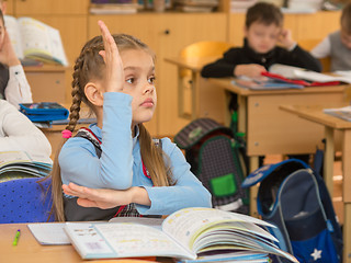 Image showing Girl schoolgirl at a lesson at school wanting to pull your hand up to answer a question