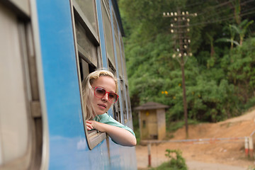 Image showing Blonde caucasian woman riding a train, looking trough window.