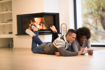 Image showing multiethnic couple used tablet computer on the floor