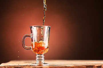 Image showing Brown splashes out drink from cup of tea on a brown background