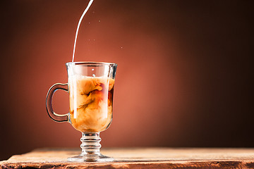 Image showing Adding milk to a cup of coffee.