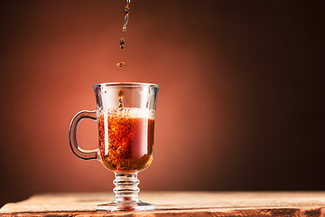 Image showing Brown splashes out drink from cup of tea on a brown background