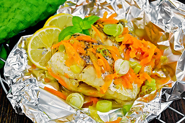 Image showing Pike with carrots and basil in foil on board