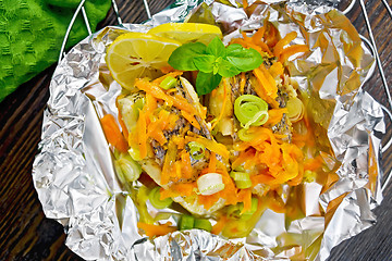 Image showing Pike with carrots and basil in foil on board top