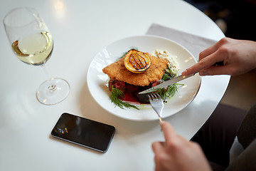 Image showing woman with smartphone eating salad at restaurant