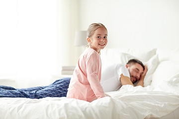 Image showing little girl waking her sleeping father up in bed
