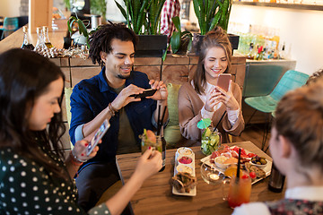 Image showing friends with smartphones and food at restaurant