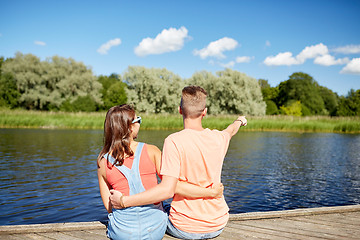 Image showing happy couple pointing finger on summer river berth