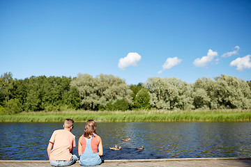 Image showing couple on river berth looking at swimming ducks